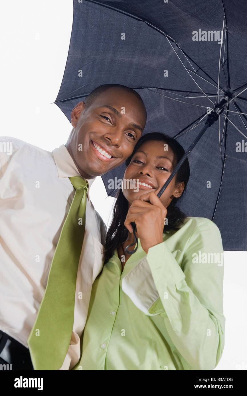Hispanic couple standing under umbrella Stock Photo
