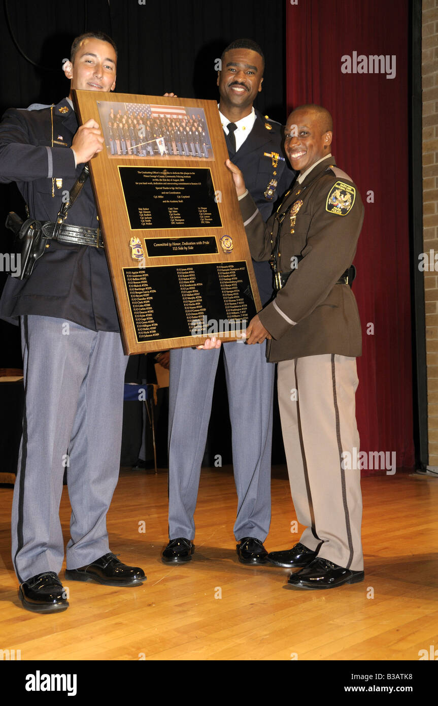 Three police hold a plaque given to the trainer of a class of police cadets at their graduation in Greenbelt, Maryland Stock Photo