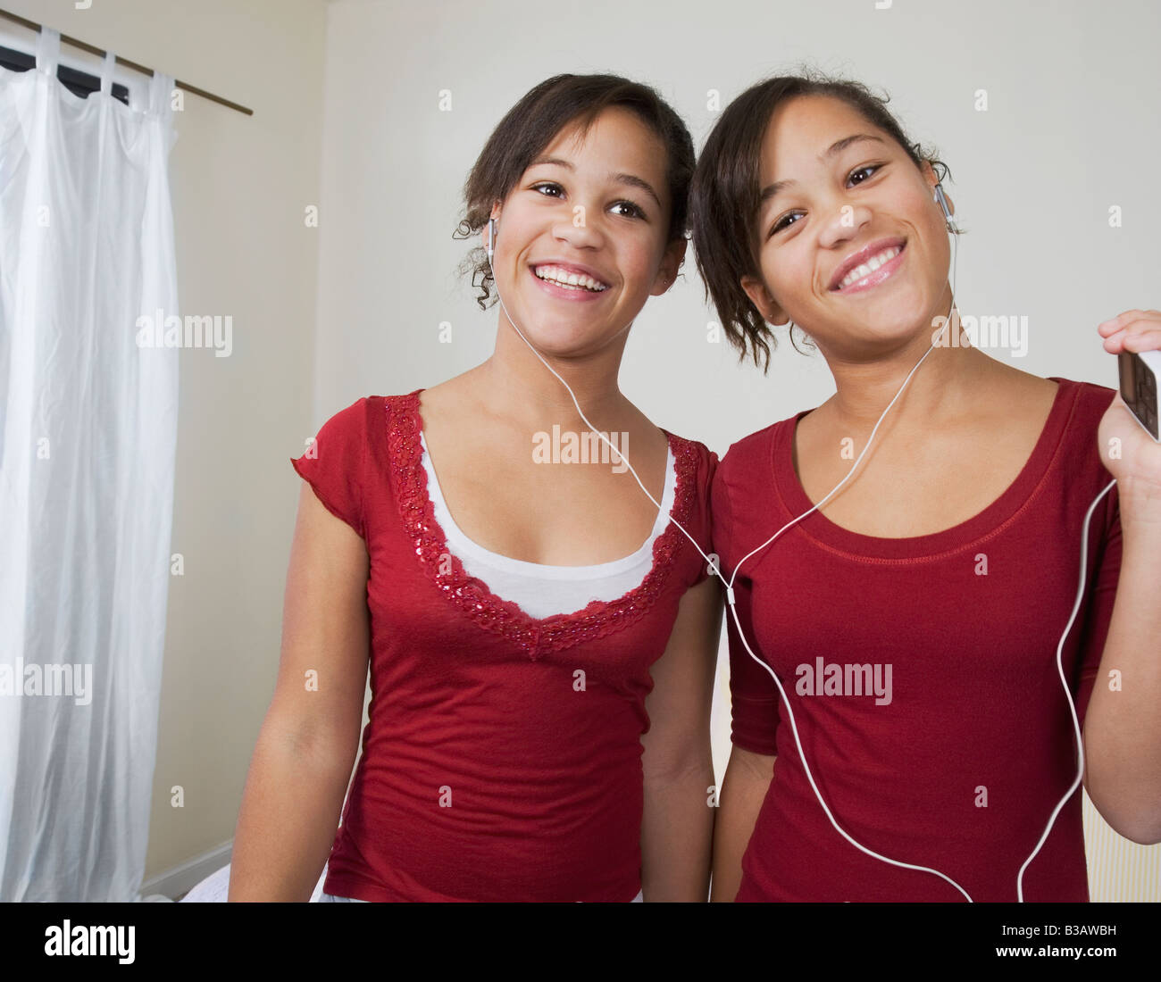 African twin sisters listening to same mp3 player Stock Photo - Alamy