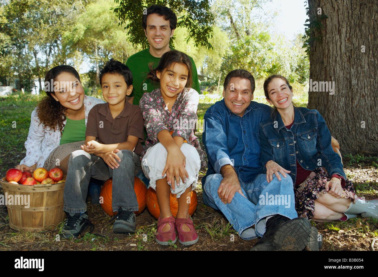Multi-ethnic family sitting under tree Stock Photo