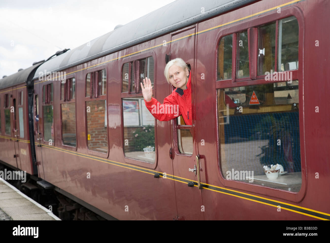 Sad farewell as person leaves on a train. Girl wearing Red Coat and blonde hair Stock Photo