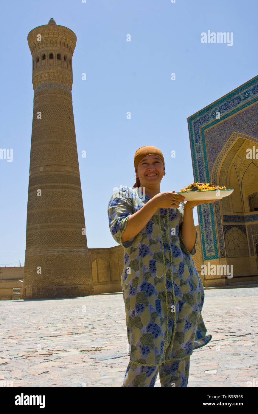 Woman with Plov in front of the Kalon Mosque and Minaret in Bukhara Uzbekistan Stock Photo