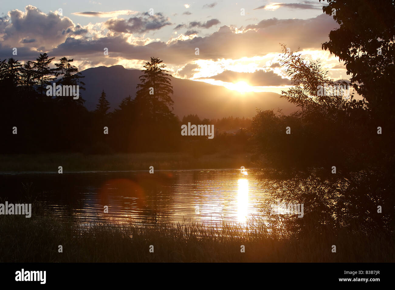 The sun going down behind Mt Washington as seen from Comox, British Columbia, Canada. Stock Photo