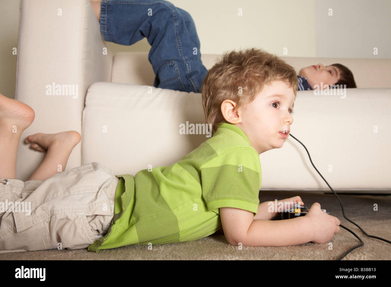 Boy Playing Video Games, Brother Lying on Sofa Stock Photo