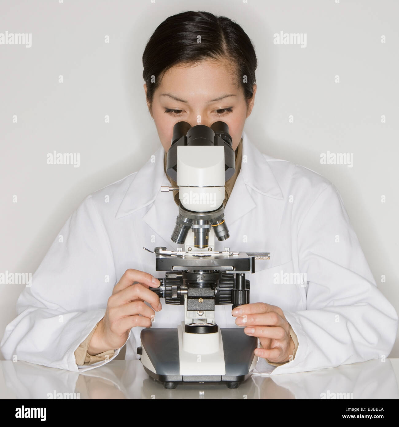 Asian female scientist looking into microscope Stock Photo