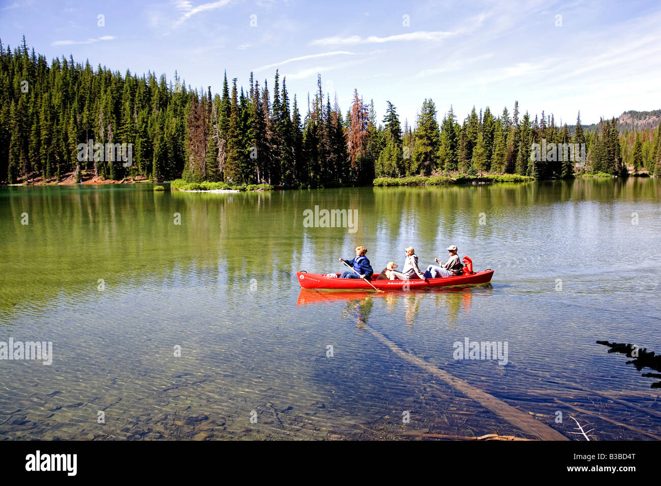 A canoe filled with visitors tours Devils Lake in the central oregon Cascades near Mount Bachelor on the CAscade Lakes Highway Stock Photo