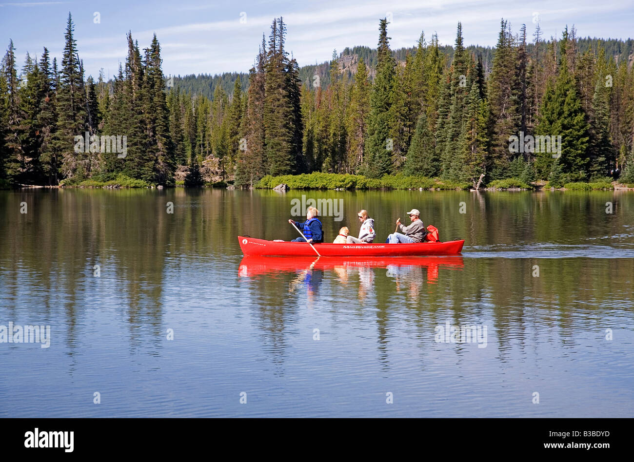A canoe filled with visitors tours Devils Lake in the central oregon Cascades near Mount Bachelor Stock Photo