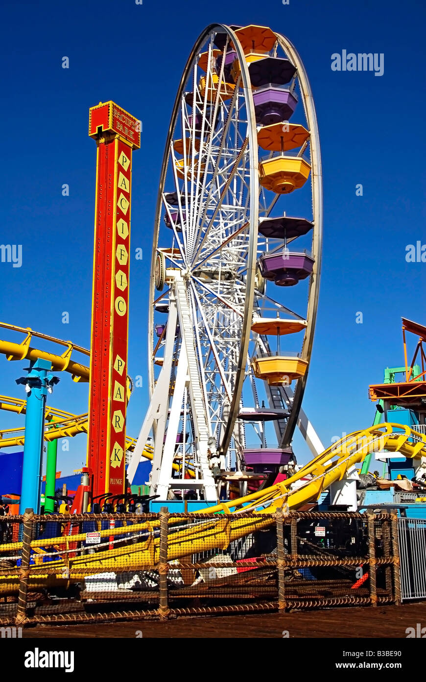 Pacific Park, Santa Monica CA pier family amusement park large Ferris wheel Roller Coaster moving over the ocean Vertical Stock Photo