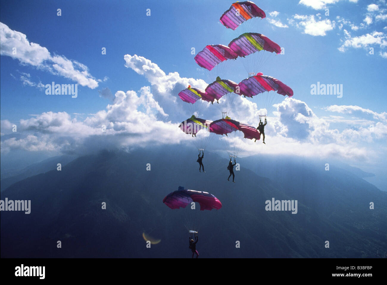 Eight Skydivers are Flying a formation together while number nine is approaching from the bottom to dock and close the diamond f Stock Photo
