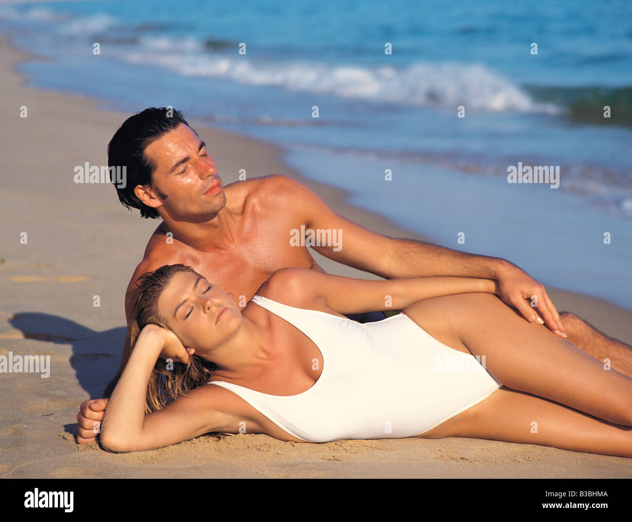 Young couple in swimsuits lying on a beach. Stock Photo