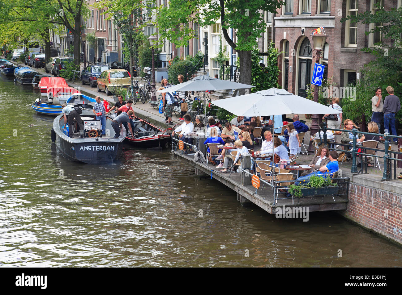 People eating and drinking besides a canal in Amsterdam, Holland Stock Photo