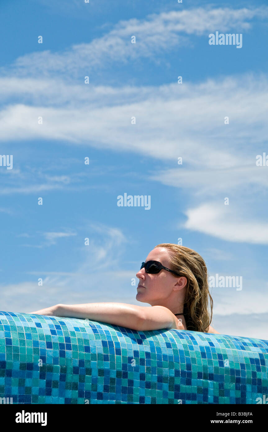 ZIHUATANEJO, Mexico - Young woman relaxing in the pool against the ocean. Stock Photo