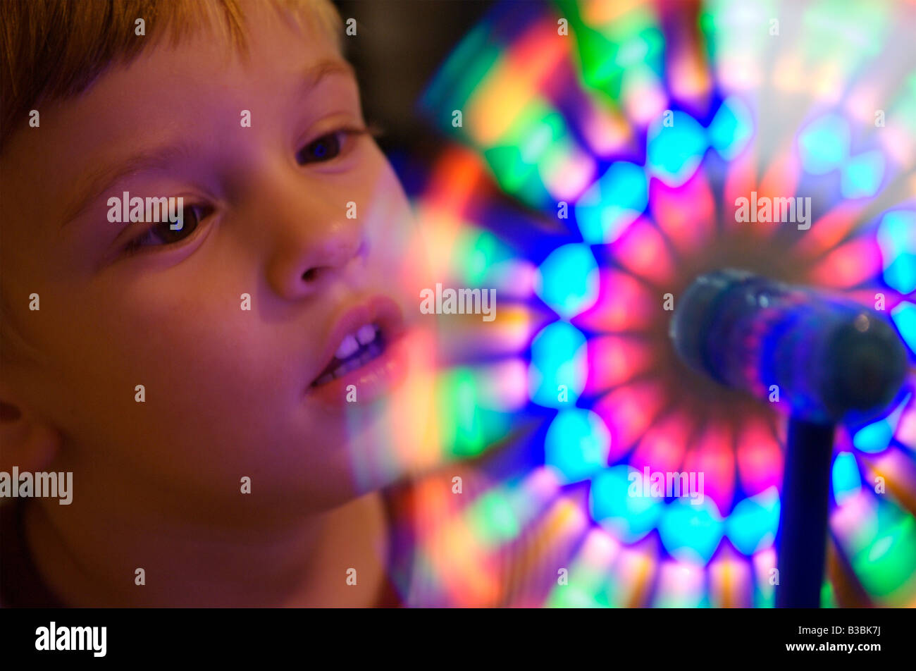 A young boy looking at a spinning colorful wheel Stock Photo
