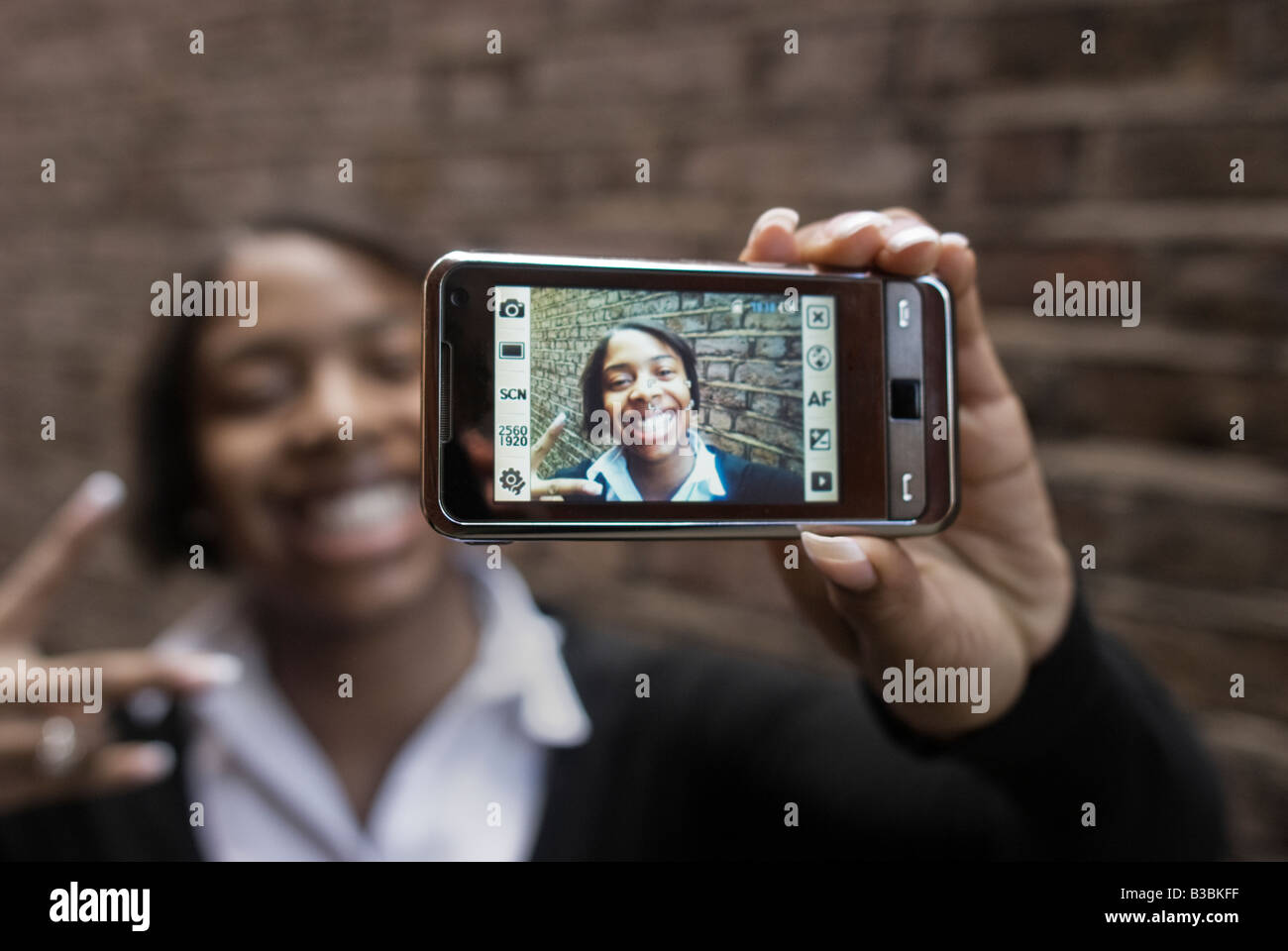 Black schoolgirl taking picture of herself on a mobile phone Stock Photo