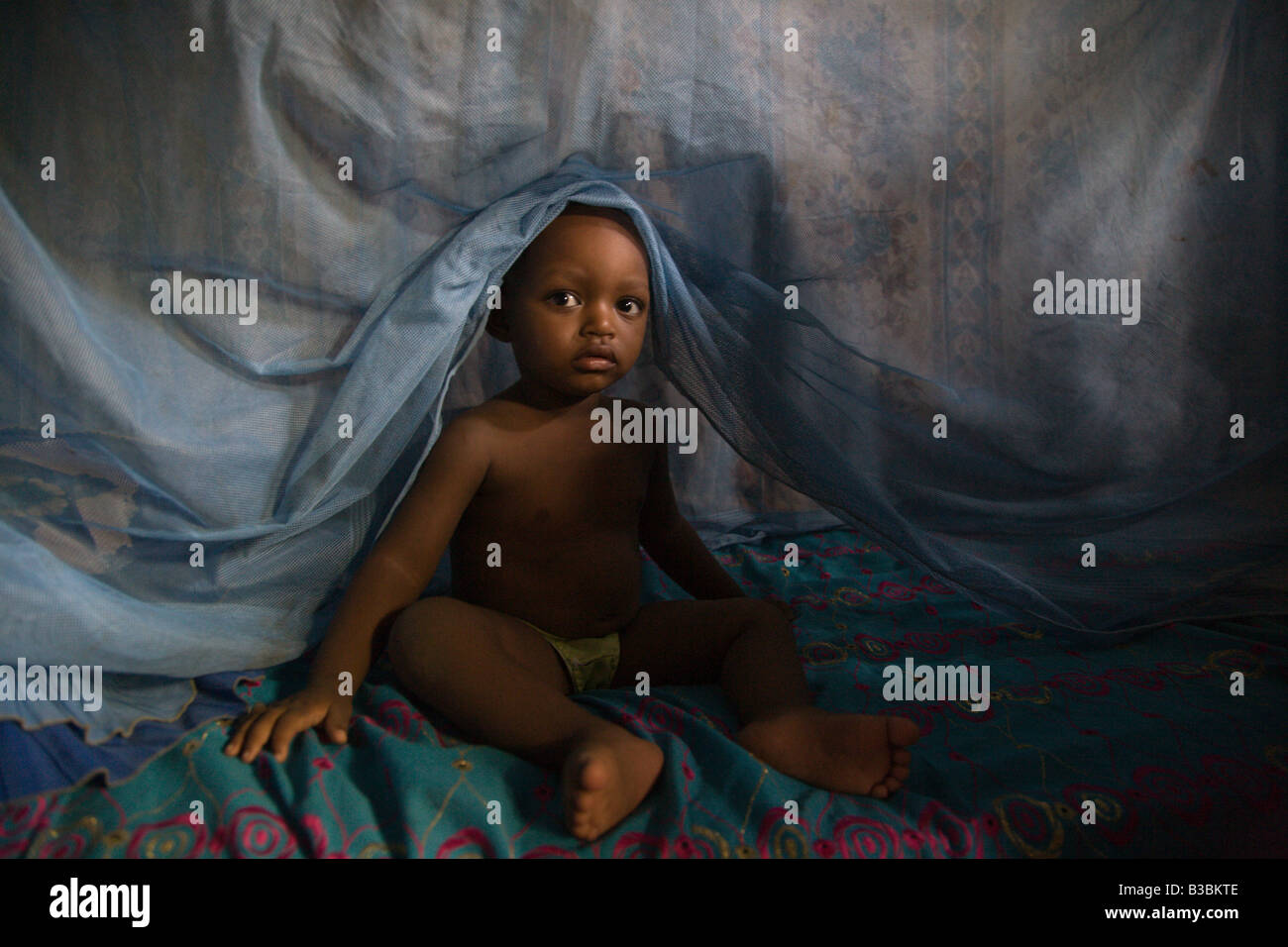 Child climbing out from under mosquito net in Kano Nigeria Stock Photo
