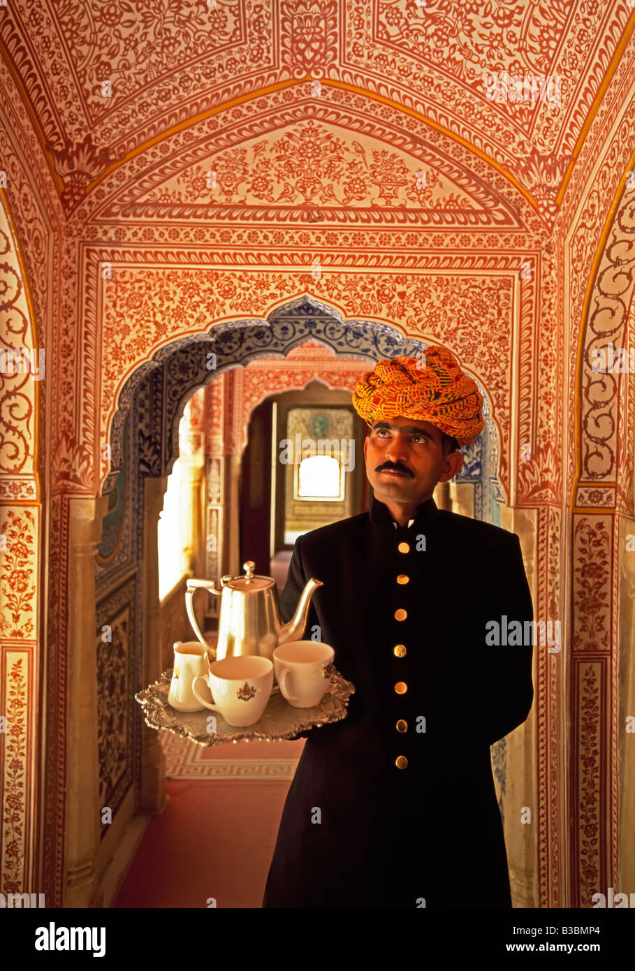 India, Rajasthan, Jaipur, Samode Palace, Waiter holding Tea Tray in ornate passageway - Model and Property released Stock Photo