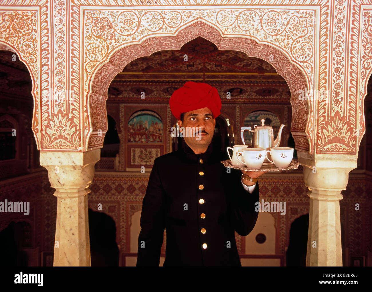 India, Rajasthan, Jaipur, Samode Palace, Waiter holding Tea Tray in ornate passageway - Model and Property released Stock Photo