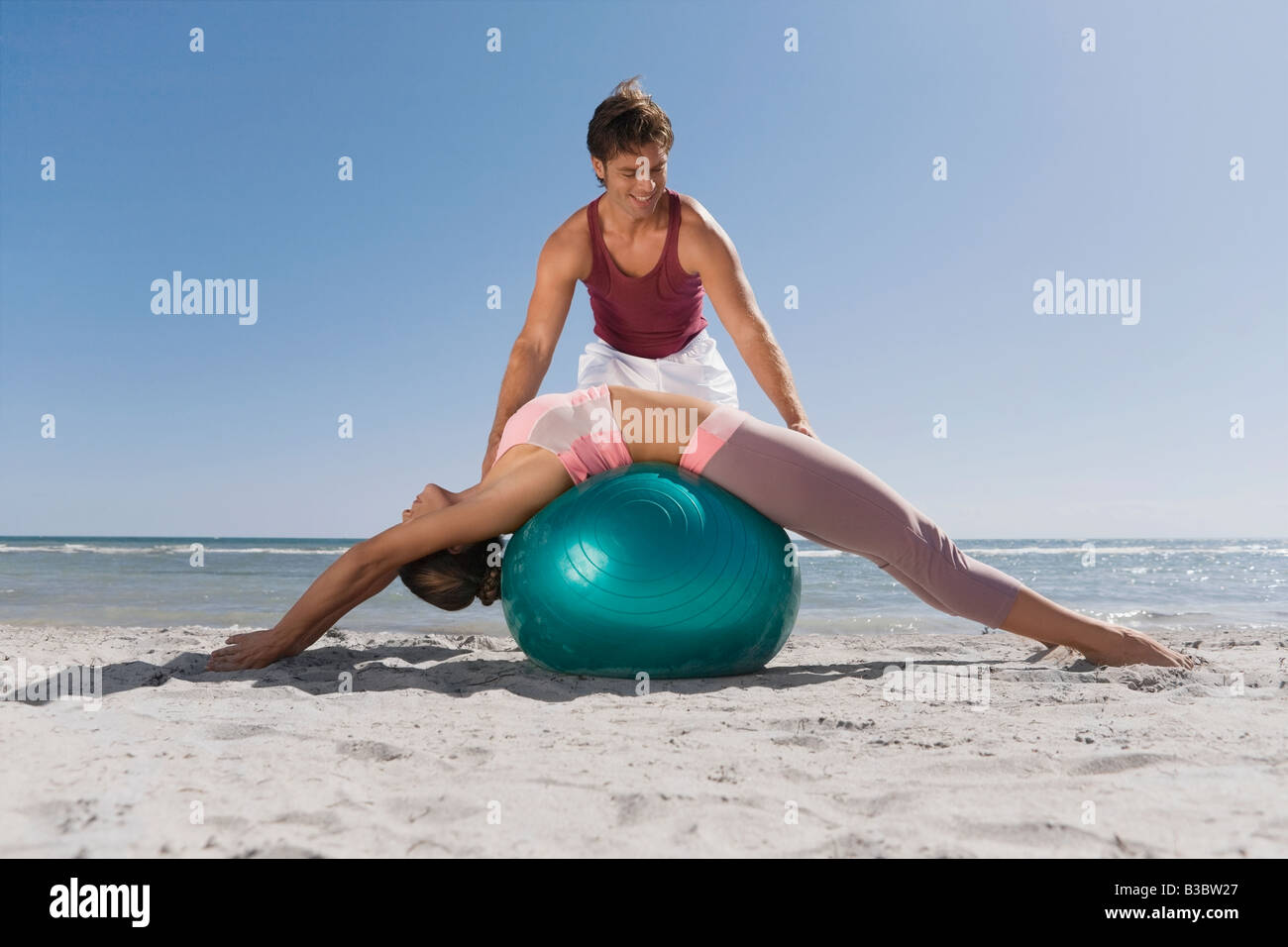 Hispanic trainer assisting woman on exercise ball Stock Photo