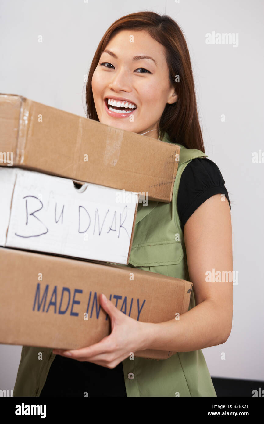 Asian woman carrying stack of packages Stock Photo