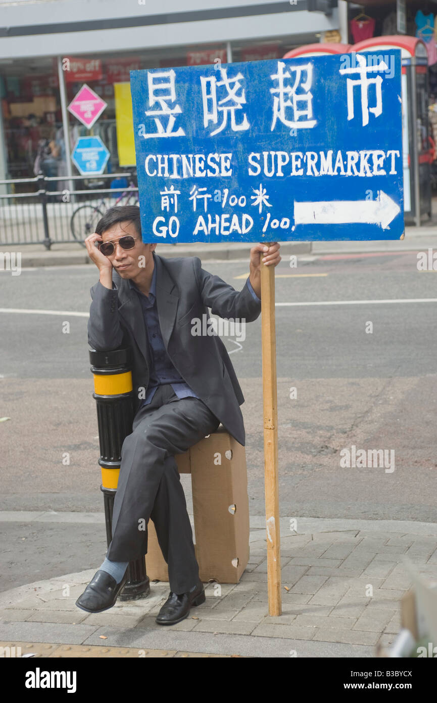 Chinese man sitting on Kingsland high road Dalston Hackney holding