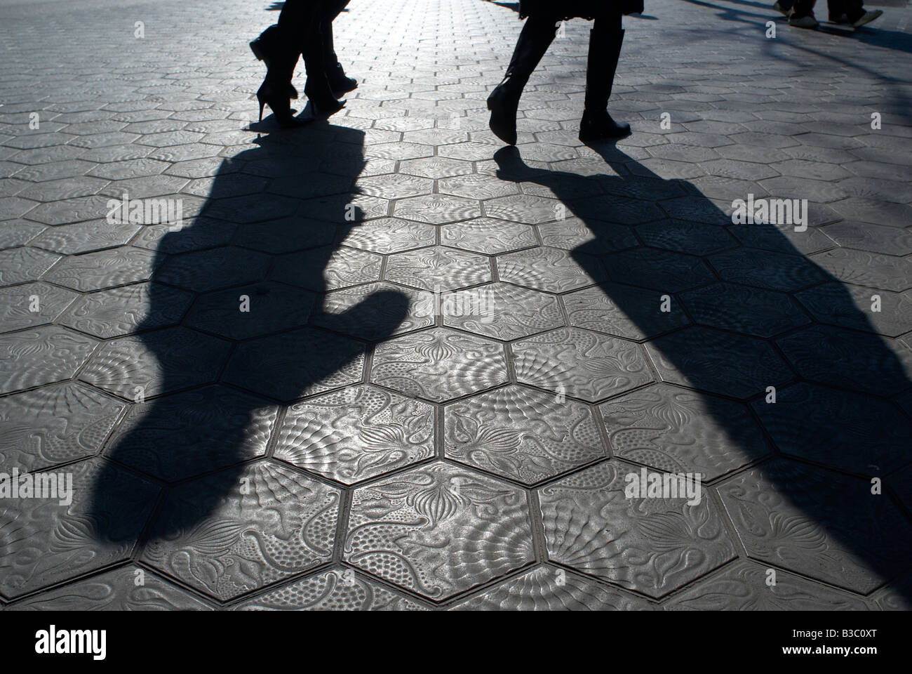 Shadows of two people walking on tiled streets Stock Photo Alamy