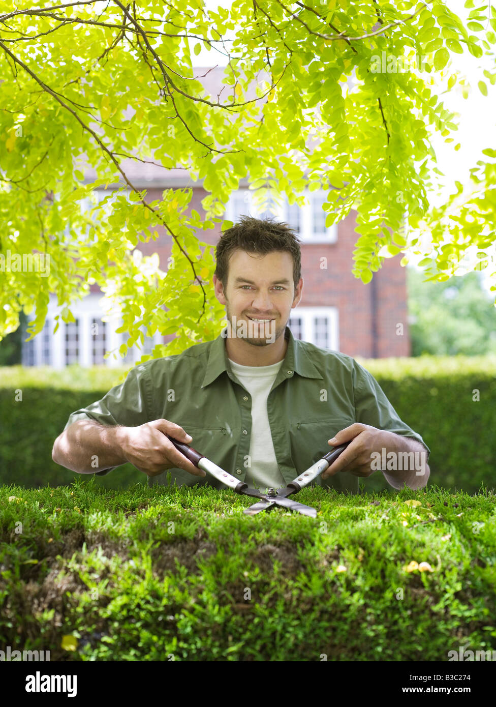 A man cutting a hedge with shears Stock Photo