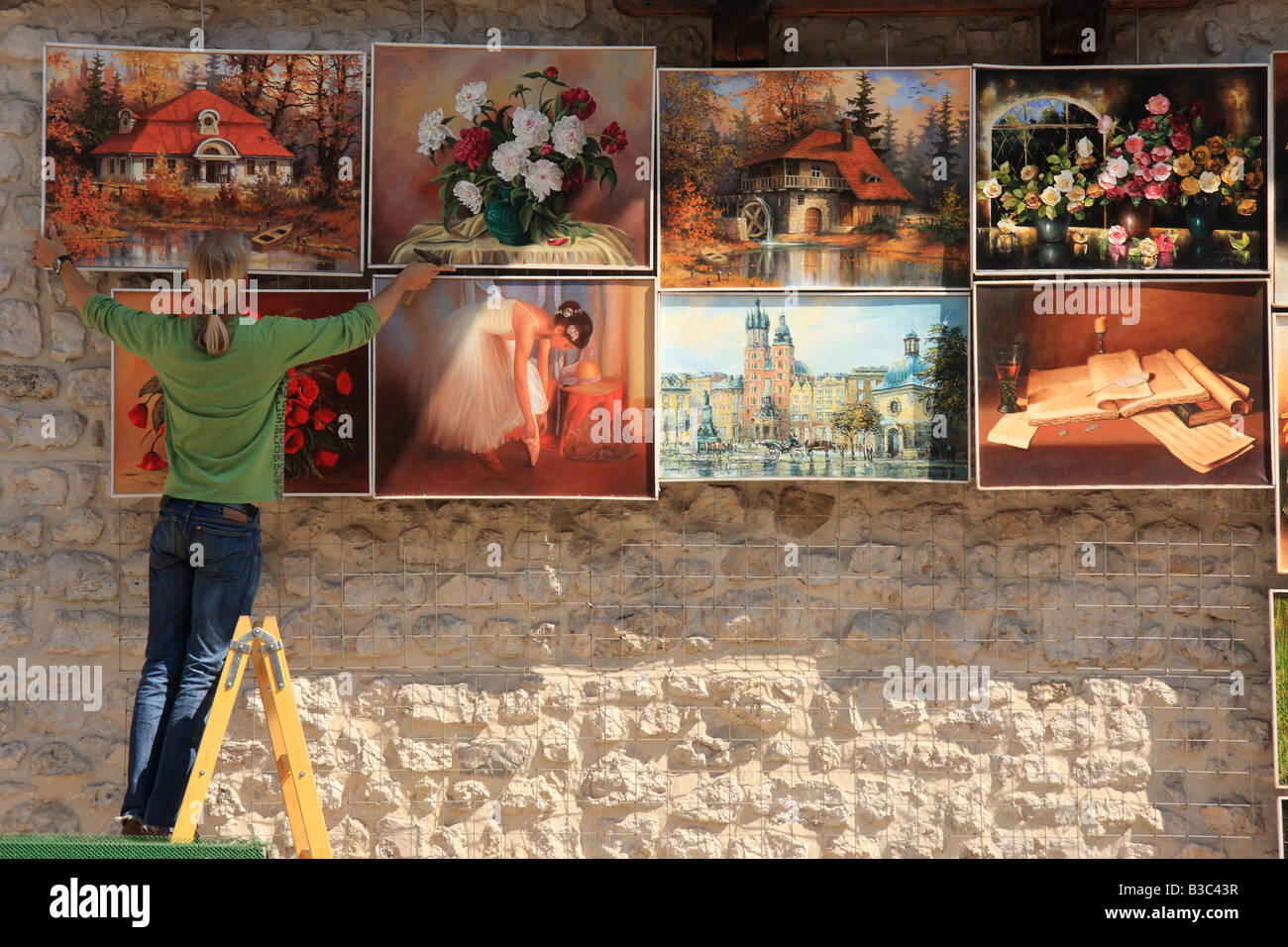 A female art seller displays her wares for sale on the wall of the Barbican in Krakow, Poland Stock Photo