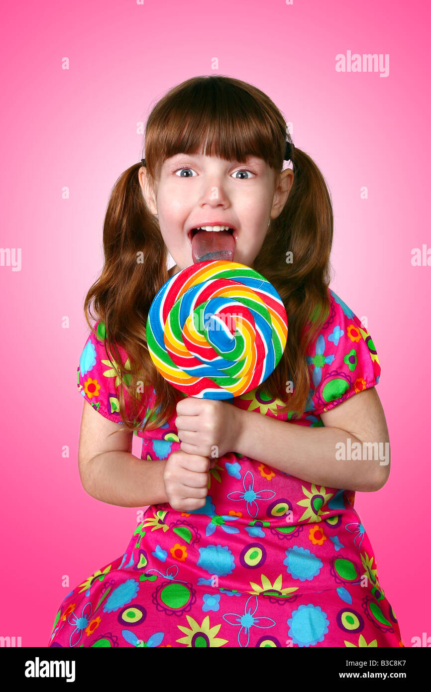Bright Pink Image of a Girl Licking a Lollipop on Pink Background Stock Photo