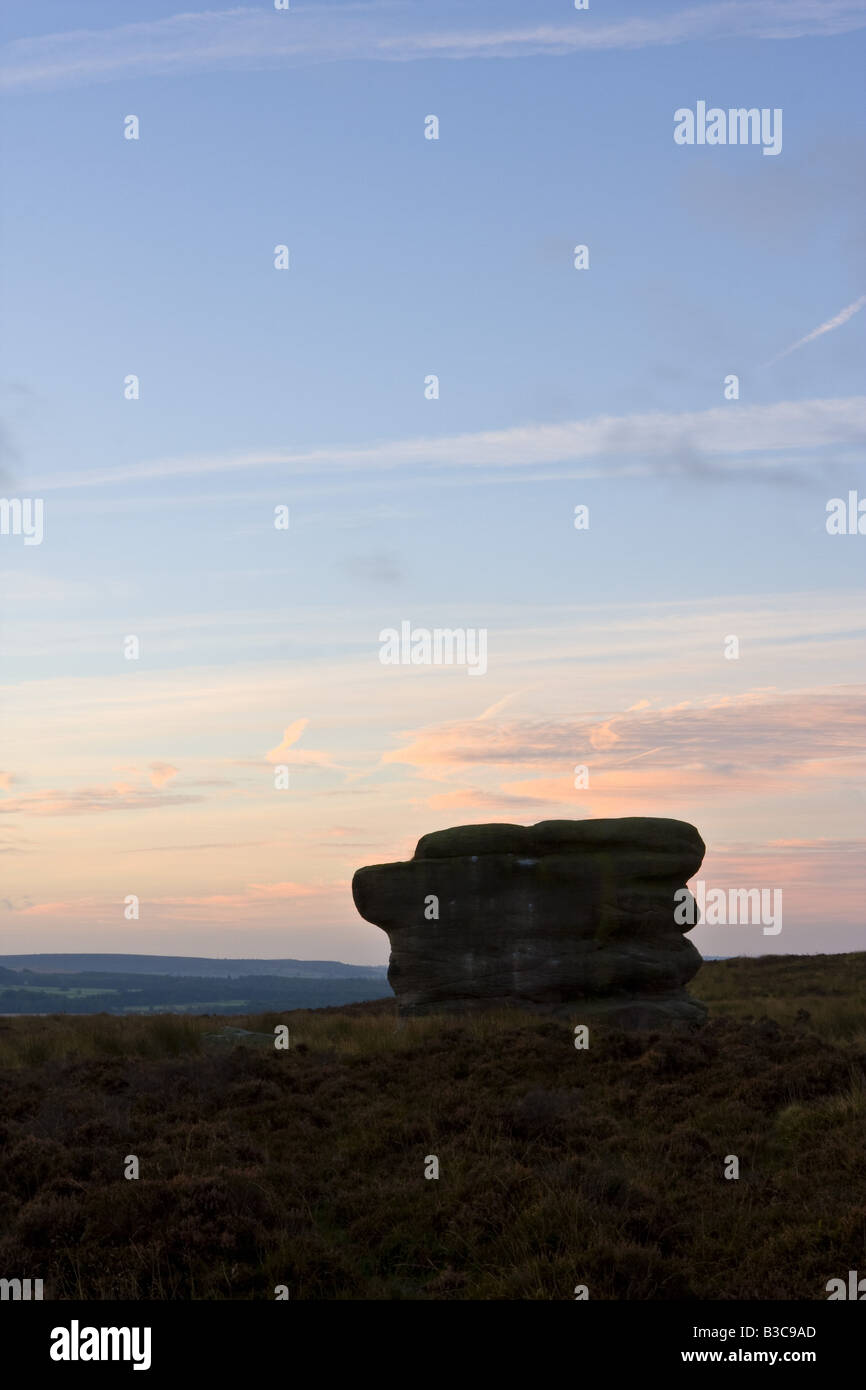 Eagle Stone in the Peak District above Curbar village in silhouette against a pre-dawn sky Stock Photo