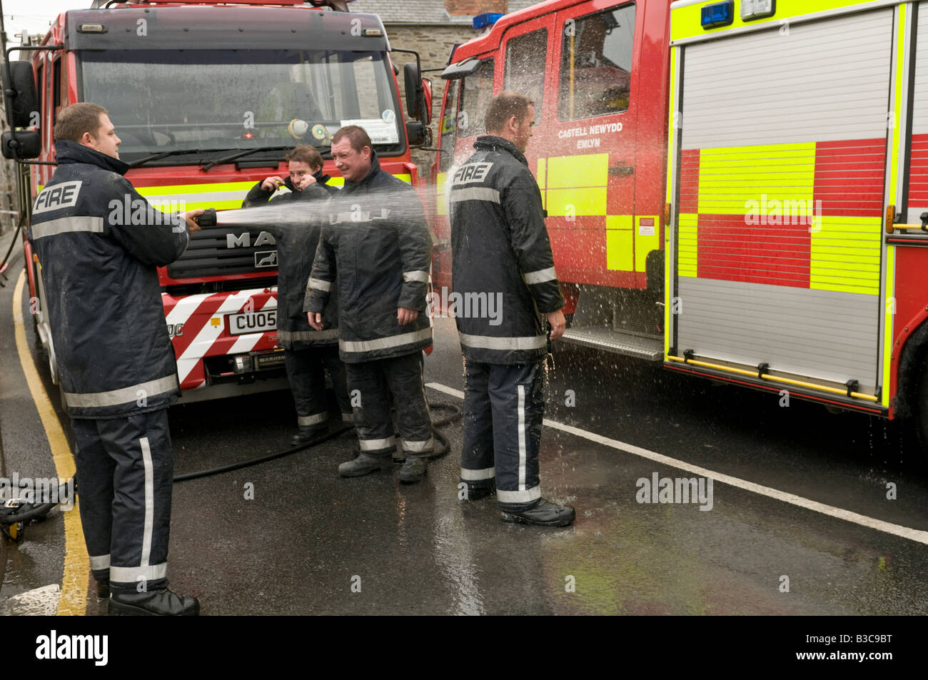 Fireman Hosing down a fellow Fire brigade officer after attending a 999 call out incident at Cardigan west wales UK Stock Photo