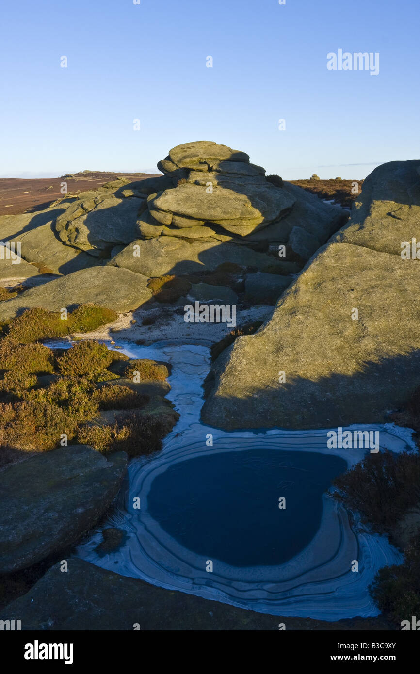 Rocks on Derwent Edge with a frozen pool in front which has circles of white frost Stock Photo