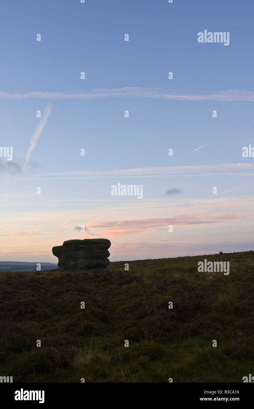 Eagle Stone in the Peak District above Curbar village in silhouette against a pre-dawn sky Stock Photo