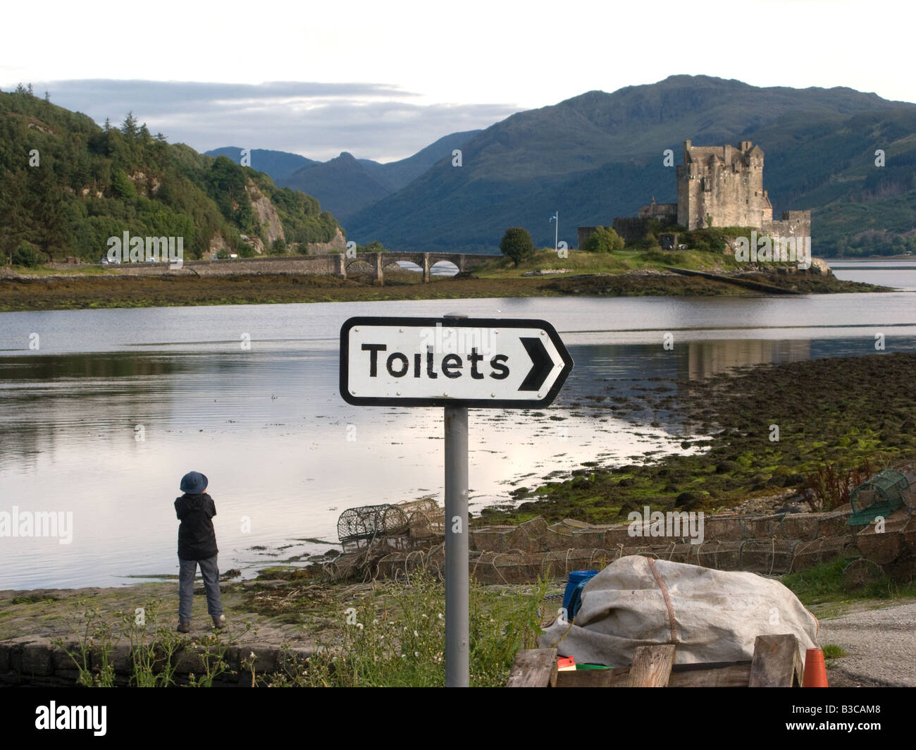A sign pointing to the public toilets near the beauty spot of Eilean Donan Castle in the Highlands of Scotland Stock Photo