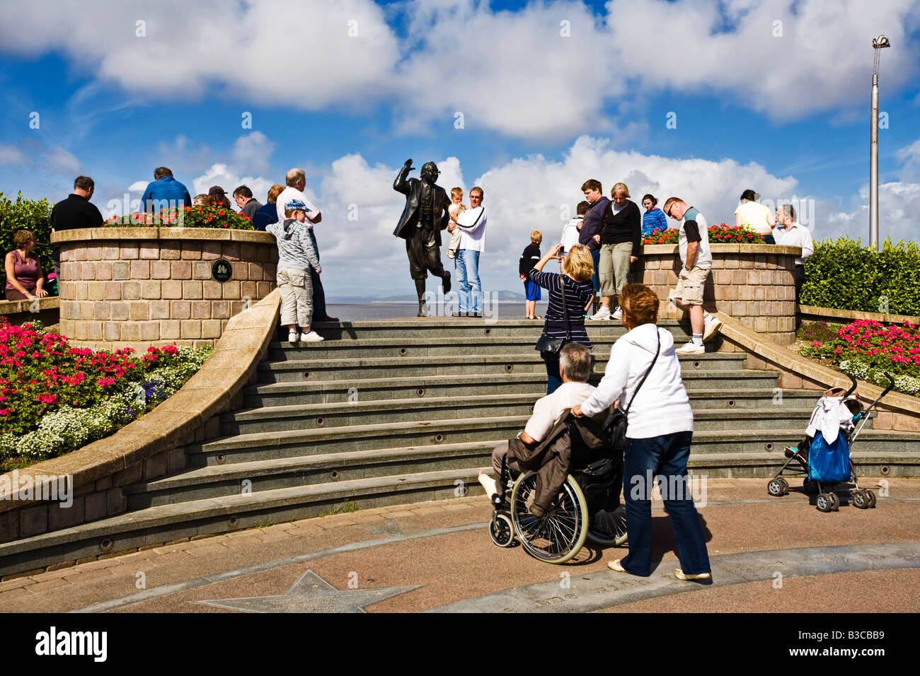Tourists having their picture taken with the Eric Morecambe bronze statue at Morecambe, Lancashire, North of England, UK Stock Photo