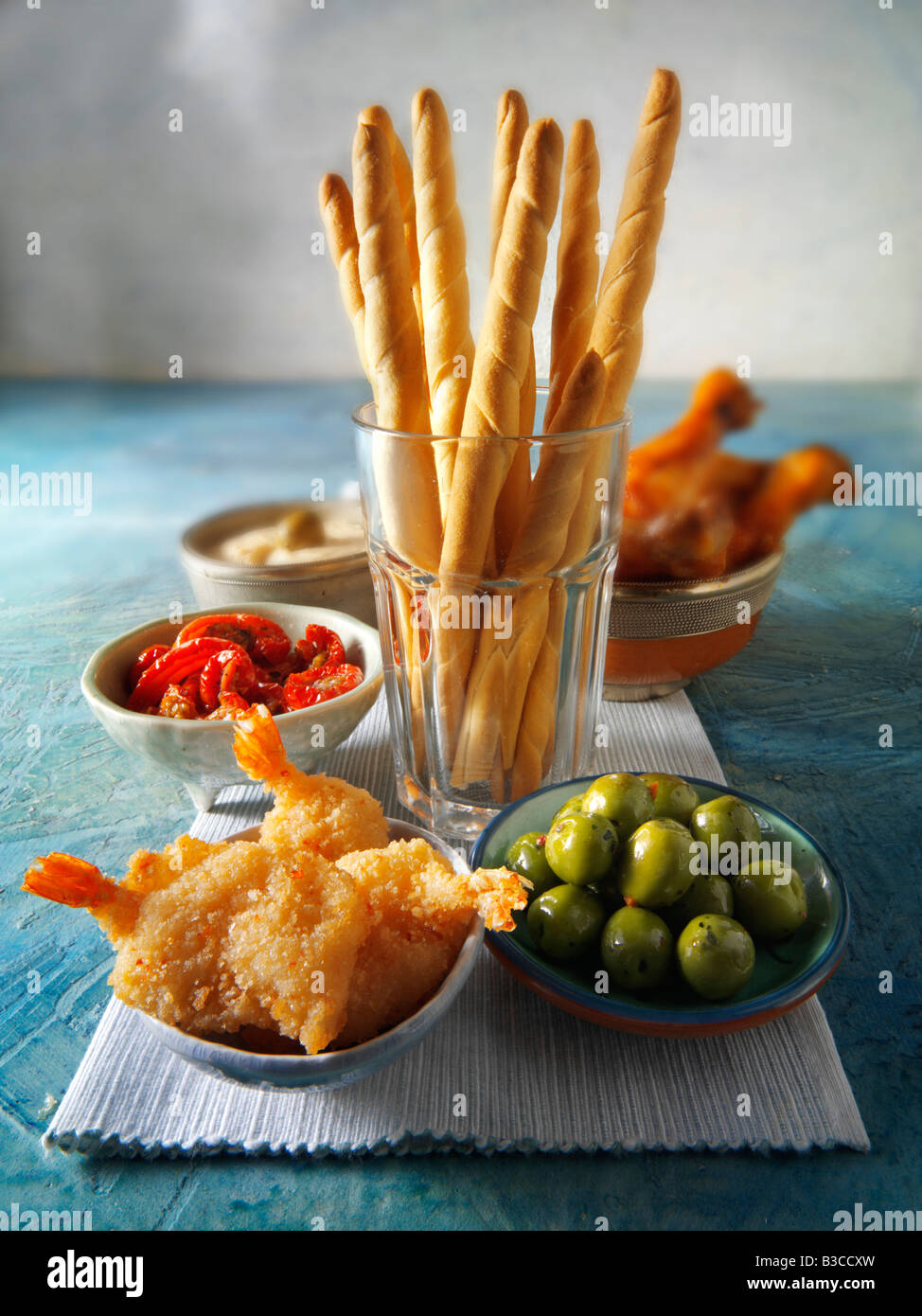 party food buffet with bread sticks, deep fried breaded prawns, green olives, marinated sun dried tomatoes, bbq chicken Stock Photo
