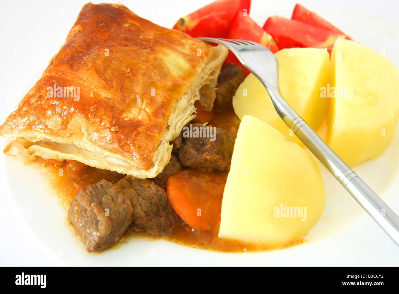 A Beef Steak Pie With Puff Pastry Crust Served With Boiled Potatoes And Tomato Wedges Stock 