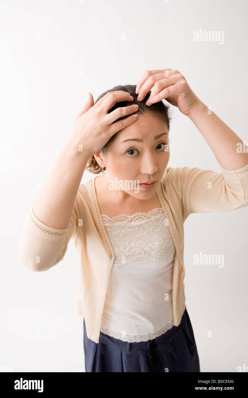 Mid adult woman checking her hair Stock Photo - Alamy