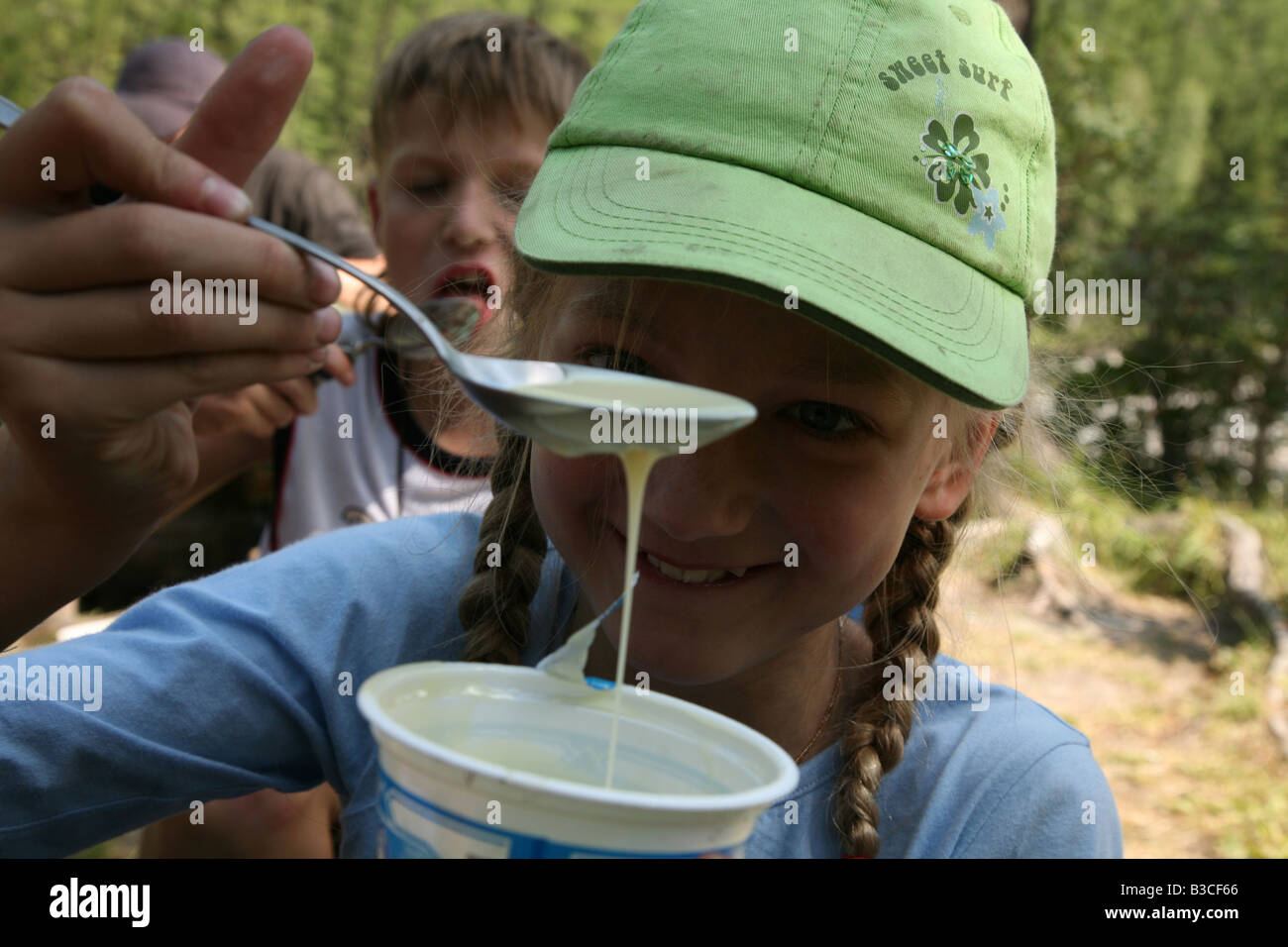 Young girl eating the spoon of condensed milk during a trekking in the