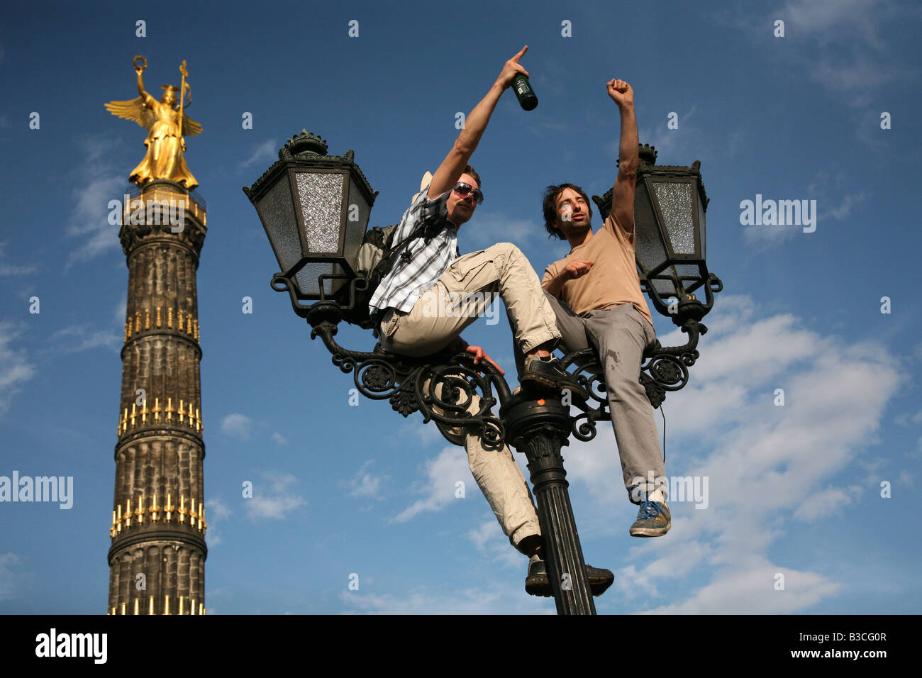 Two men sitting at the old lantern in front of the Victory Column during the Christopher Street Day Pride in Berlin, Germany Stock Photo