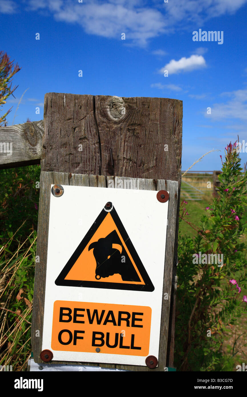 A warning sign stating 'BEWARE OF BULL' on a gatepost. Stock Photo