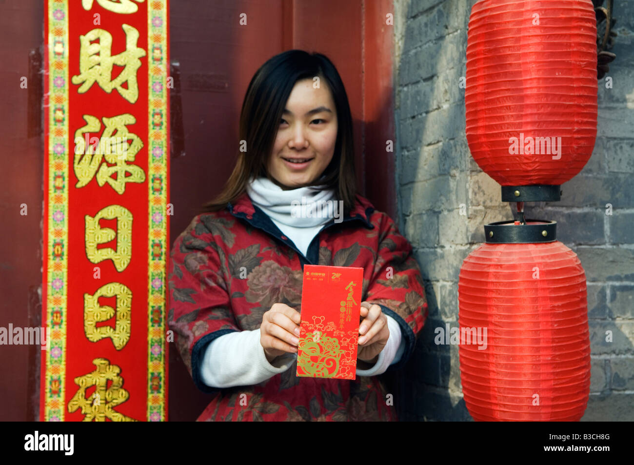 China, Beijing. A Chinese girl wearing traditional Chinese style clothes holding a Hongbao envelope which is received with money by students and children during Chinese New Year Spring Festival (MR). Stock Photo