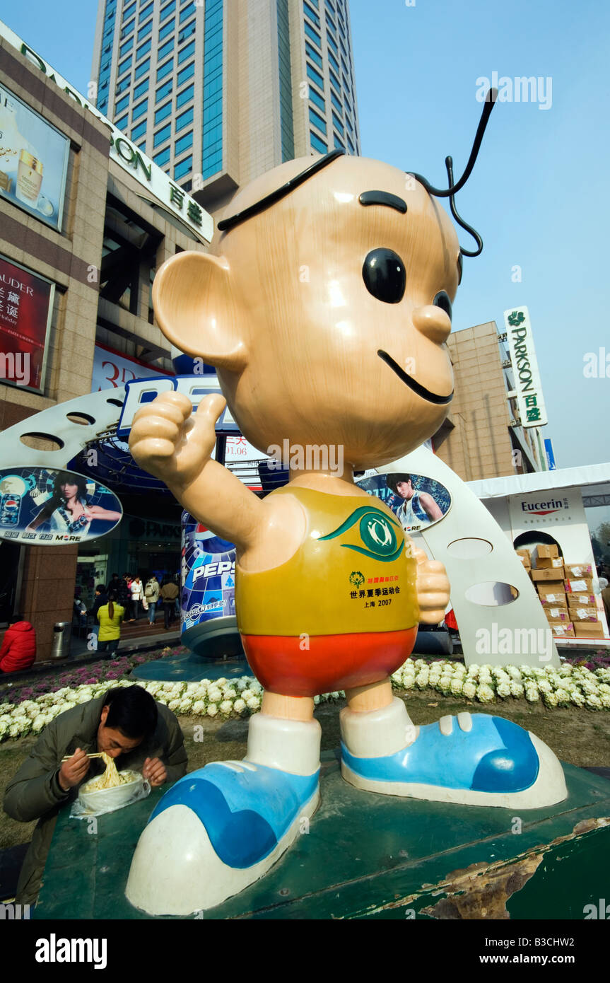China, Shanghai. French Concession area - a cartoon character statue and a man eating noodles on the street. Stock Photo