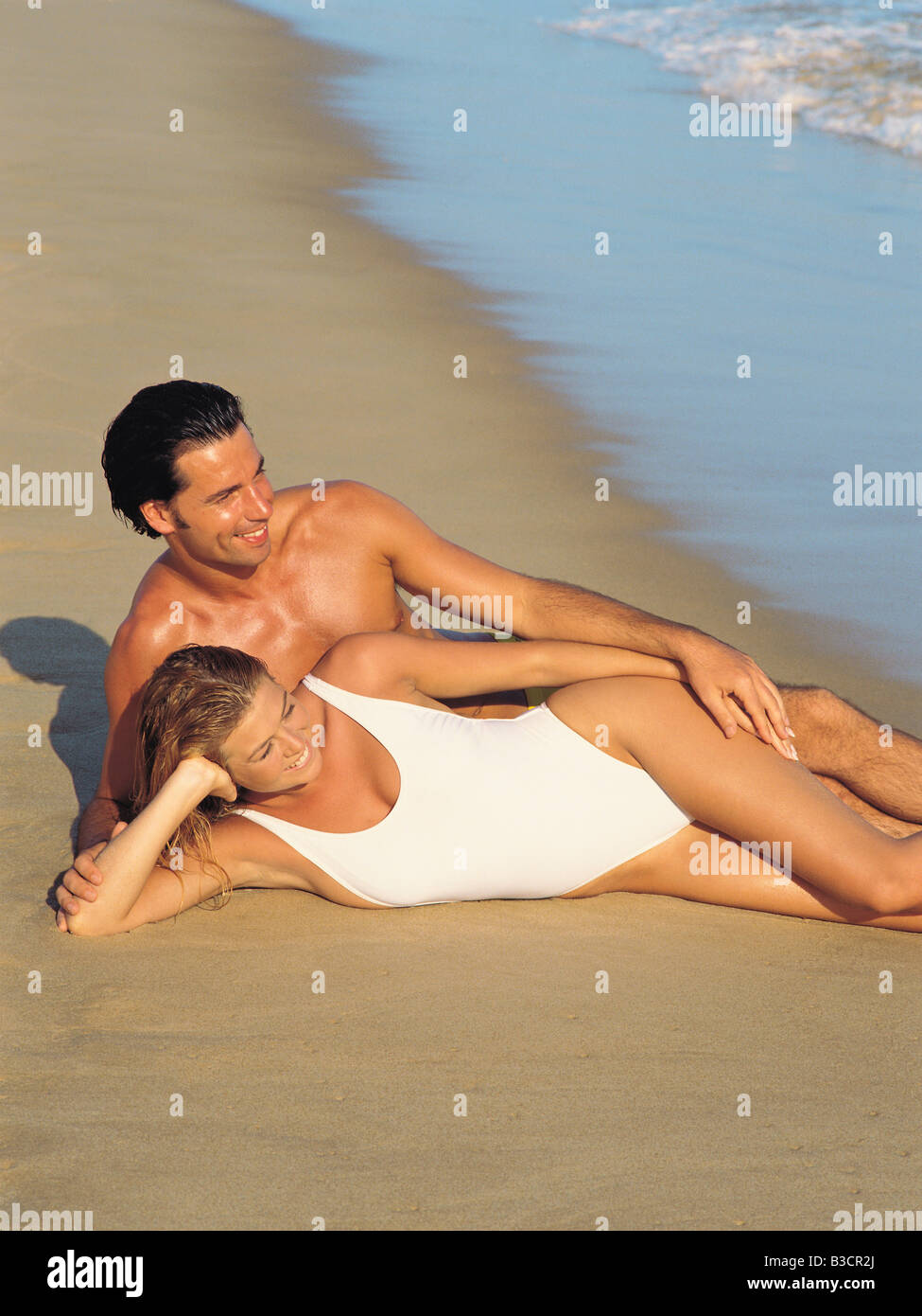 Young couple in swimsuits lying on a beach. Stock Photo