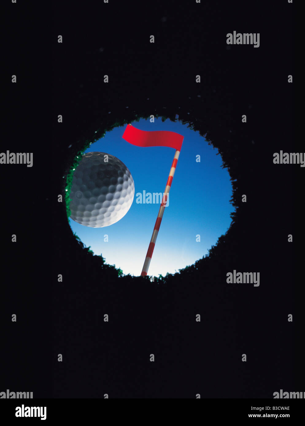 Golf ball on edge of hole. View from inside hole. Stock Photo