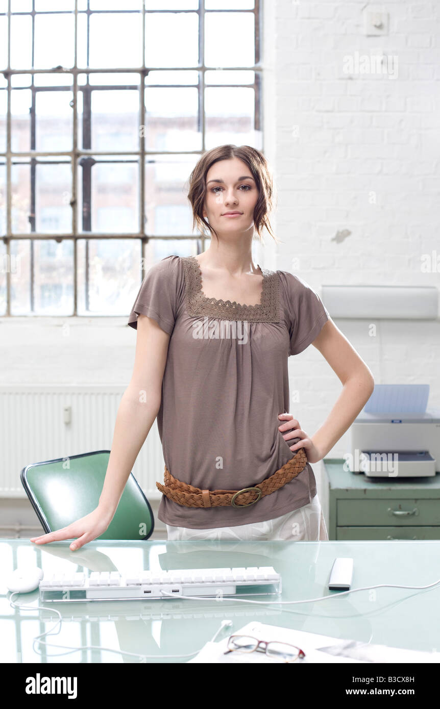 Young businesswoman in office standing at desk Stock Photo - Alamy
