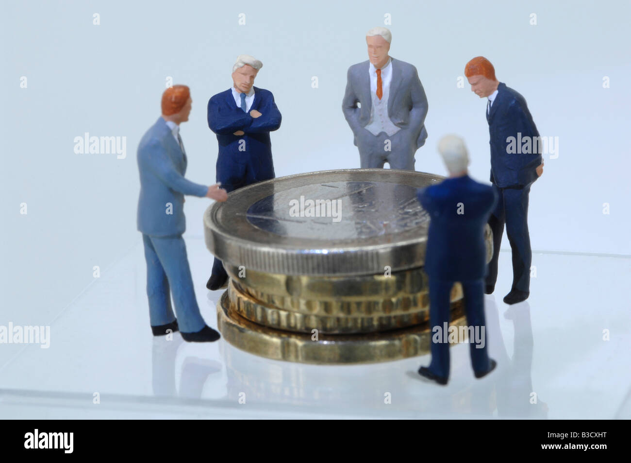 Business men figurines looking at coins Stock Photo Alamy