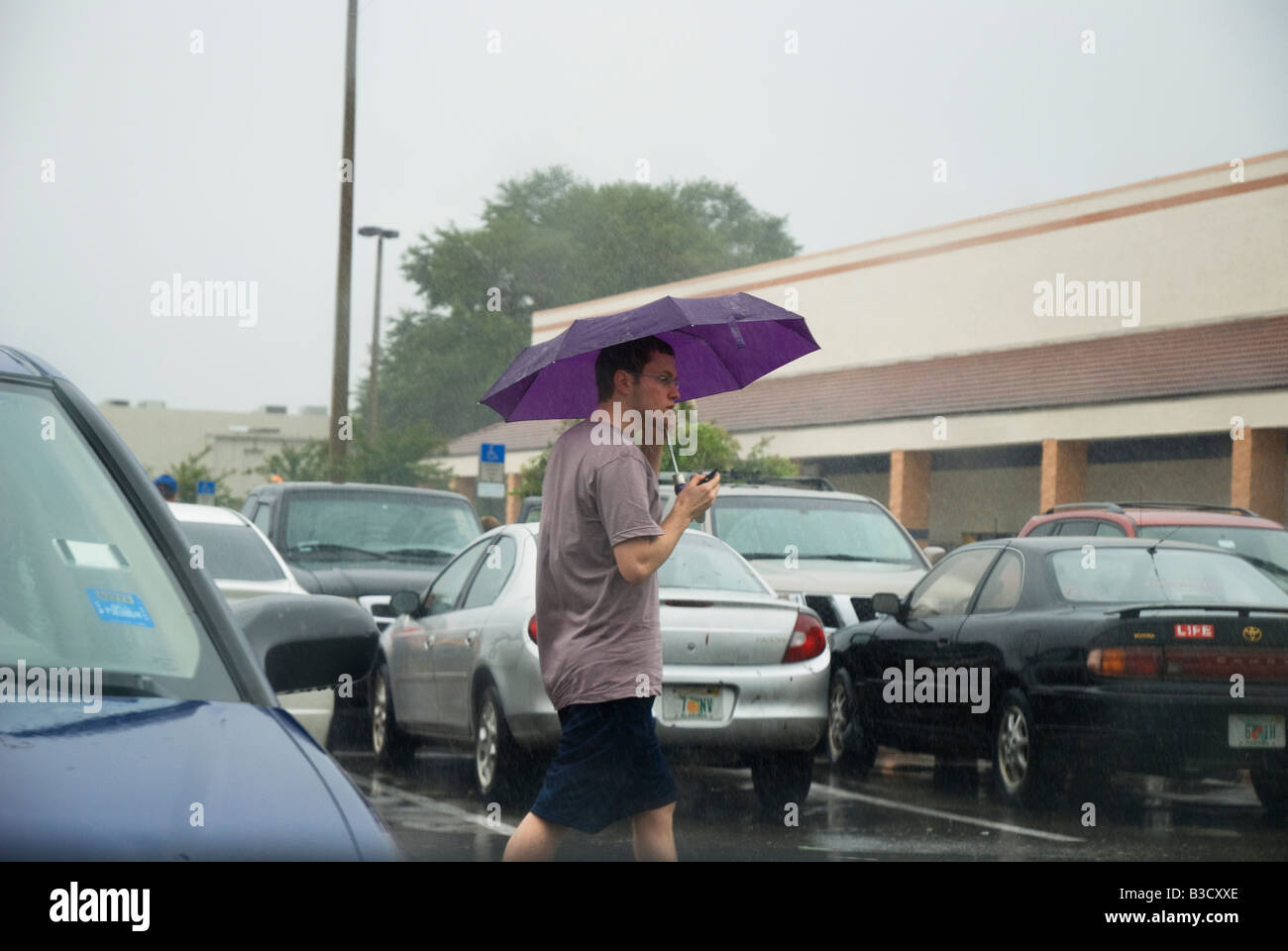 man takes refuge under umbrella in rain from Tropical Storm Fay