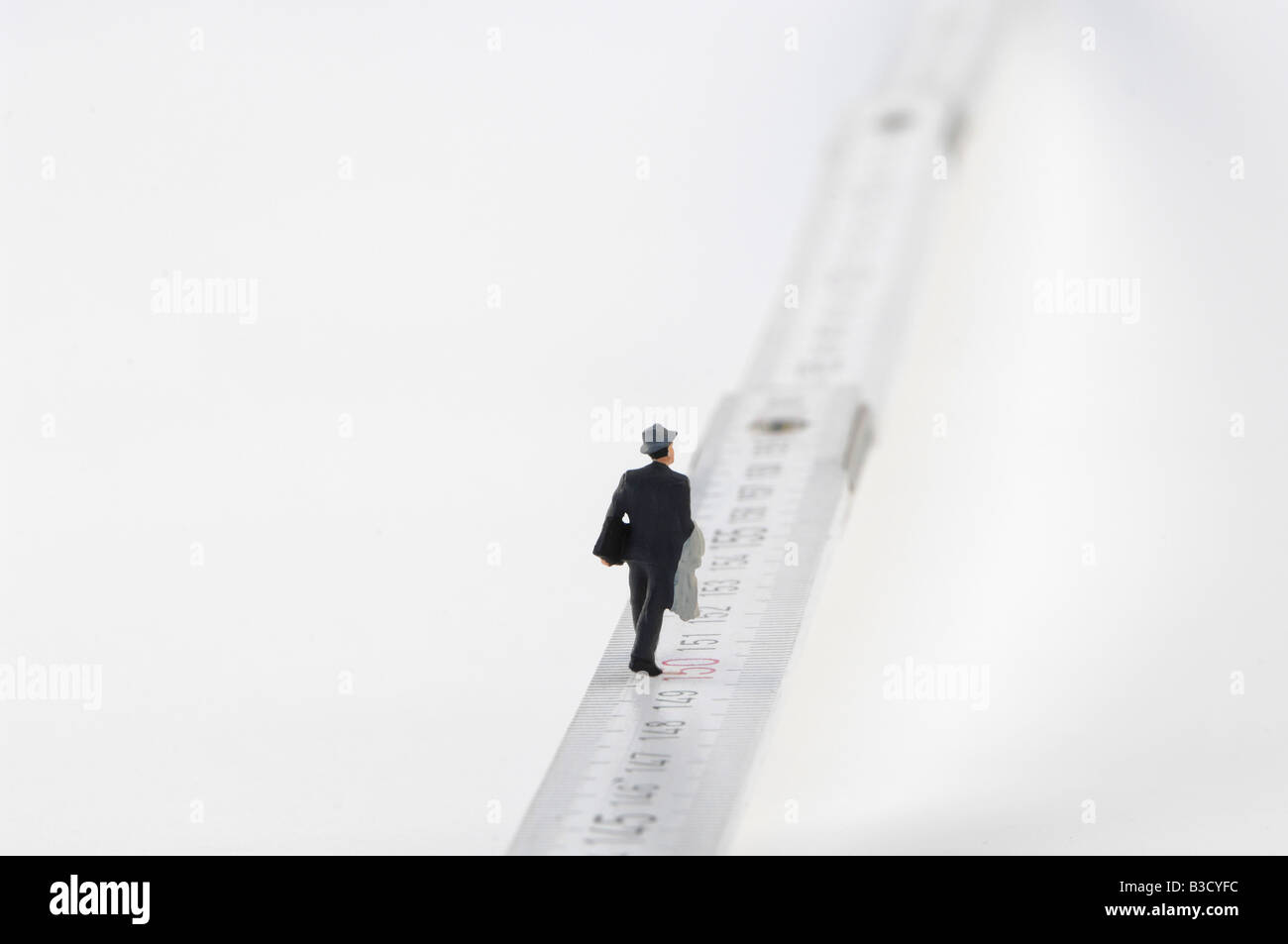 Business man figurine walking on measuring tape Stock Photo