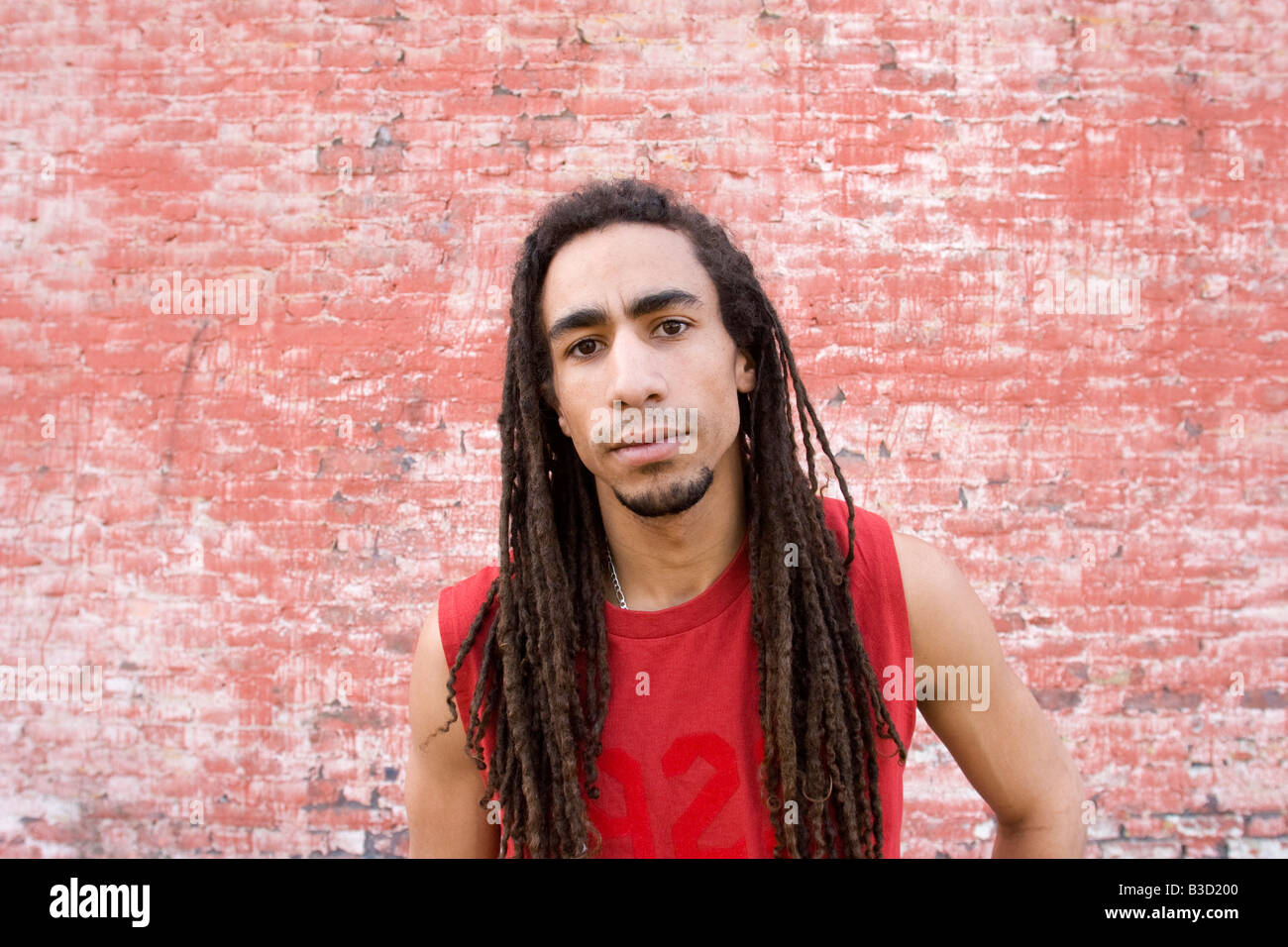 Young man standing in front of brick wall, portrait Stock Photo - Alamy