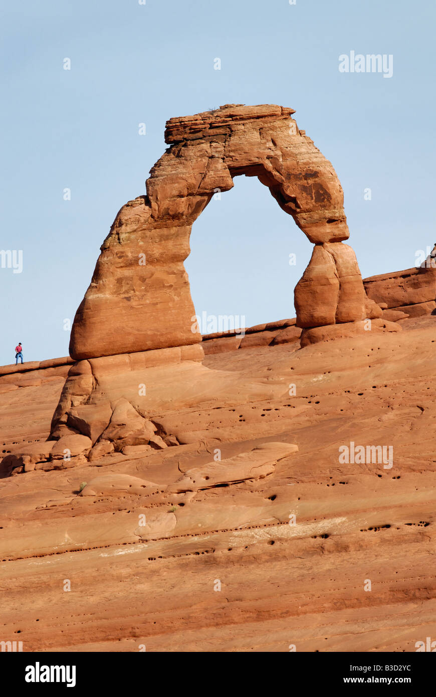 Hiker Standing Near Delicate Arch in Arches National Park Utah Stock Photo